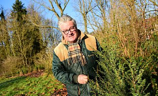 Friedhelm Begemann mit einem Wacholder. Die Pflanzen sind vielfältig nutzbar. Sie bieten Tieren Schutz, sind gut für das Ökosystem und ihre Beeren sind nicht nur Grundlage für Schnaps, sondern auch als Gewürz einsetzbar. - Nadine Uphoff Friedhelm Begemann mit einem Wacholder. Die Pflanzen sind vielfältig nutzbar. Sie bieten Tieren Schutz, sind gut für das Ökosystem und ihre Beeren sind nicht nur Grundlage für Schnaps, sondern auch als Gewürz einsetzbar. - Nadine Uphoff