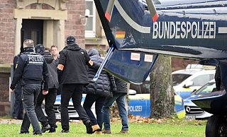 Eine Person (2.v.r.) wird von Polizisten aus einem Hubschrauber gebracht. - Uli Deck/dpa Eine Person (2.v.r.) wird von Polizisten aus einem Hubschrauber gebracht. - Uli Deck/dpa