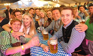 Zahlreiche Gäste erscheinen in traditionellen Dirndl und Krachledernen im Festzelt. Dazu fließt bayerisches Bier, und von der Bühne erklingt passende Musik. - Nicole Ellerbrake