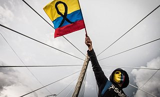 Ein maskierter Demonstrant schwenkt die kolumbianische Flagge. - Foto: Juan Pablo Otalvaro M/dpa Ein maskierter Demonstrant schwenkt die kolumbianische Flagge. - Foto: Juan Pablo Otalvaro M/dpa