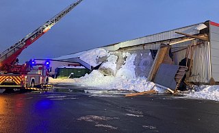 Schneemassen haben das Vordach der Produktionshalle heruntergedrückt. „Begraben" sind unter anderem zwei Lkw-Sattelauflieger. Die Holzbalken, die das Vordach stützten (wie beispielsweise rechts zu sehen), reichen in die eigentliche Halle herein und sind teilweise hochgedrückt worden. - Feuerwehr Bad Salzuflen Schneemassen haben das Vordach der Produktionshalle heruntergedrückt. „Begraben" sind unter anderem zwei Lkw-Sattelauflieger. Die Holzbalken, die das Vordach stützten (wie beispielsweise rechts zu sehen), reichen in die eigentliche Halle herein und sind teilweise hochgedrückt worden. - Feuerwehr Bad Salzuflen