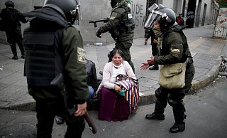 Umgeben von Polizisten, sitzt eine Unterst&uuml;tzerin von Evo Morales auf einem B&uuml;rgersteig in La Paz. In Bolivien ist es erneut zu Zusammenst&ouml;&szlig;en zwischen Anh&auml;ngern und Gegnern des zur&uuml;ckgetretenen Pr&auml;sidenten gekommen. - Foto: Natacha Pisarenko/AP/dpa