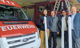 Roman Marks (Gebäudemanager, von links), Jörg Diekmann (Leiter der Freiwilligen Feuerwehr Augustdorf), Lamine Traoré (Klimaschutzmanager) und Dr. Andreas J. Wulf (Bürgermeister) mit den neuen Leuchtröhren. Foto: Gemeinde Augustdorf - Gemeinde Augustdorf