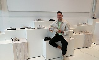 Jonas Gurcke im Showroom von Wortmann. Hier werden die neuen Modelle besprochen und vorgestellt. Im Hintergrund sind die neuen Sandalen der Premium-Kollektion "Newd.Tamaris." zu sehen. In der Hand hält Jonas Gurcke sein neues Liebliengsstück aus der Outdoor-Kollektion. - Freya Köhring