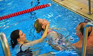 Manfred Krumsiek erklärt Chiara Wibbeke (links), wie das Schleppen einer zu rettenden Person funktioniert. Melina Schau simuliert dabei die zu rettende Person. - Nicole Ellerbrake