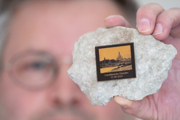Torsten Daae, Geschäftsführer im Dresdner Laden «Catapult», hält einen Stein des abgerissenen Brückenteils der eingestürzten Carolabrücke mit einer Plakette in der Hand. - © Sebastian Kahnert/dpa