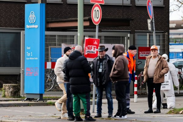 Mitarbeiter von Thyssenkrupp Steel stehen während einer Mahnwache vor einem Werkstor. - © Christoph Reichwein/dpa