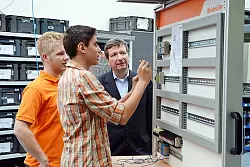 Yannic Micke (links), Azubi zum Mechatroniker, erkl&auml;rt Sch&uuml;ler Kariem Abou-Anany die Arbeiten eines Mechatronikers. Auch Vorstandssprecher Dr. Peter K&ouml;hler (rechts) nutzt die M&ouml;glichkeit, sich auszutauschen. - &copy; Foto: privat