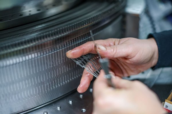 Eine Mitarbeiterin der Terrot GmbH montiert die Stricknadeln für eine Großrundstrickmaschine. Der Hersteller von Strickmaschinen steht wie viele deutsche Maschinenbauer vor dem Problem des Fachkräftemangels. - © Jan Woitas/dpa