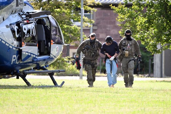 Der Tatverdächtliche wurde in Karlsruhe von bewaffneten Polizisten in Spezialausrüstung vom Helikopter zu einer Wagenkolonne gebracht. - © Uli Deck/dpa