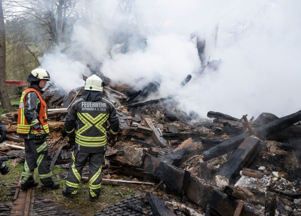Feuerwehrleute stehen neben den noch rauchenden Trümmern des ehemaligen Hauses des «Kannibalen von Rotenburg». - © Boris Roessler/dpa