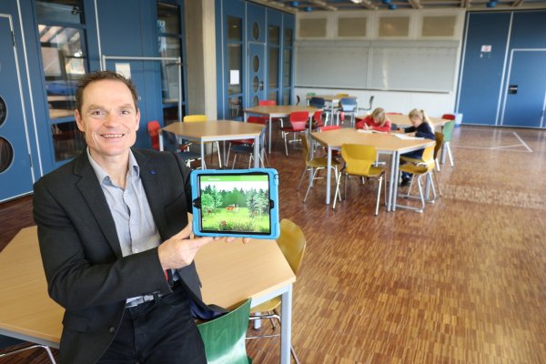 Oliver Dudek ist neuer Schulleiter der Gesamtschule Aspe. Er sitzt in Zeiten von Corona im Raum für die Notbetreuung für Kinder von Eltern aus systemrelevanten Berufen. Im Hintergrund sitzten Eileen (10, links) und ihre Zwillingsschwester Emily (10) aus der fünften Klasse über einigen Aufgaben. Ansonsten ist die Schule aktuell leer gefegt, die Schüler erhalten ihre Unterrichtsmaterialien in digitaler Form - etwa auf ihr Tablet. - © Alexandra Schaller