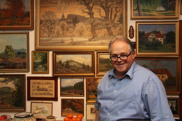 Der Hermann ist omnipräsent: Wilfried Mellies vor einer Wand mit Gemälden in seinem Wohnhaus. Fast jedes zeigt das Hermannsdenkmal oder eine Landschaftszene aus Hiddesen und Umgebung. - © Jana Beckmann