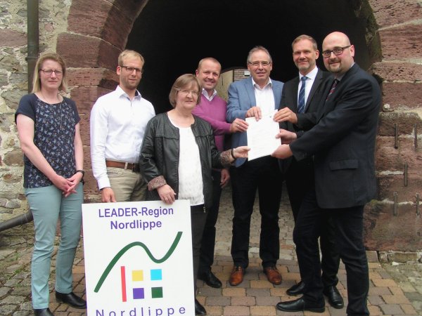 Die Regionalmanager Diana Rieke und Borris Ortmeier sowie die vier Bürgermeister Monika Rehmert, Mario Hecker, Friedrich Ehlert und Jürgen Schell nehmen den Förderbescheid von Konstantin Plümer von der Bezirkregierung entgegen (von links). - © Wulf Daneyko