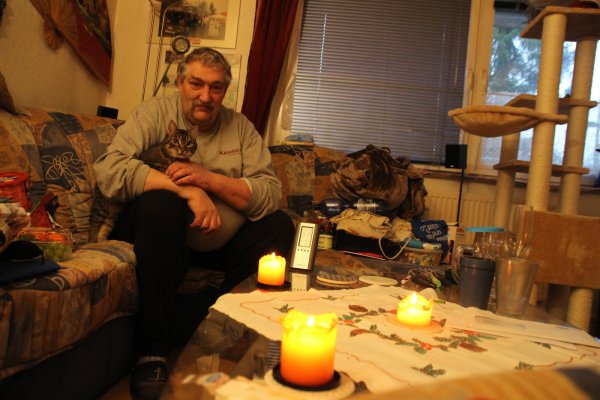 Thorsten Albutat (55) sitzt mit seiner Katze "Hasi" in der Wohnung in Sennestadt. Er friert. In diesem Moment zeigt das Thermometer eine Temperatur von 12 Grad Celsius an. - © Ingo Kalischek