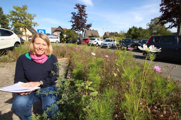 Zwei Bereiche ihrer Arbeit: Henrike Sieker, Klimaschutzmanagerin der Gemeinde Kalletal, an einer Blühwiese auf dem Parkplatz hinter dem Rathaus. Mobilität und Umwelt gehören zu den Themen, mit denen sie sich befasst. Foto: Jens Rademacher - © Jens Rademacher