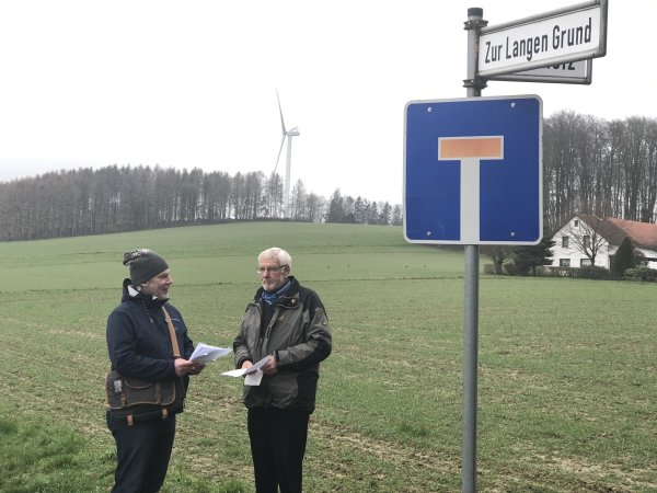 Eric Hagedorn (links) und Friedhelm Jasper stehen am Ende der Siedlung Lohholz – im Hintergrund dreht sich bereits ein Wüstener Windrad. Das neue wäre mehr als doppelt so hoch. - © Till Brand