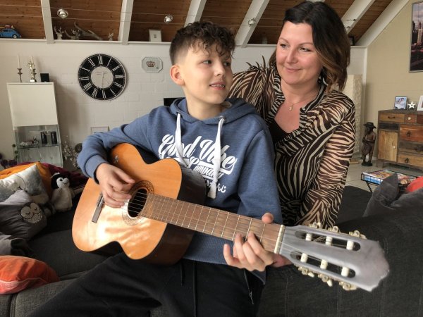 Luc und Sandra Kiefer sitzen auf der Couch im Wohnzimmer. Seit gut vier Jahren spielt der 13-Jährige Gitarre. - © Sven Kienscherf
