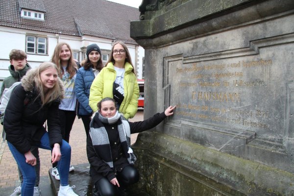 Denkmal für einen Revolutionär: John, Anastacia, Jessy, Charlotte, Djellza (von links) stehen neben dem Denkmal von Franz Hausmann, dessen Leben und Wirken demnächst Unterrichtsthema sein wird. Buket (kniend) zeigt auf das Geburtsdatum: den 26. Februar 1818. - © Dieter Asbrock