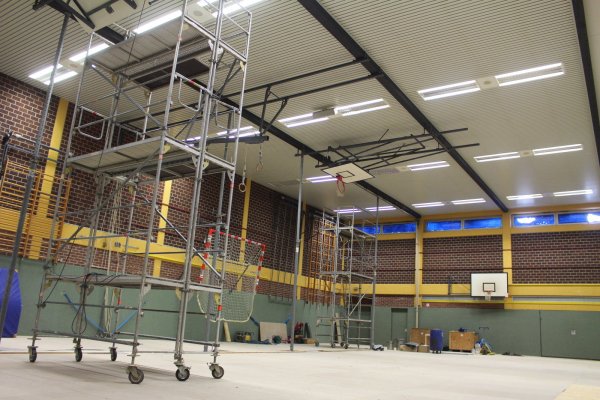 In der Turnhalle 2 des Schulzentrums an der Ulmenallee wird fleißig gearbeitet. Über die hohen Gerüste gelangen die Arbeiter in den Zwischenraum der Decke. Von dort aus können die Holzleimbinder saniert werden. - © Michaela Weisse