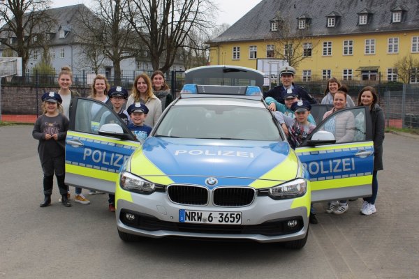 Neue Erfahrung: Die Schüler der Christian-Morgenstern-Schule schauen sich zusammen mit den angehenden Erzieherinnen, der Schulsozialarbeiterin Petra Niggemann (Dritte von rechts) und Polizist Christian Gutowski (Sechster von rechts) einen Polizeiwagen an.  - © Nadine Uphoff