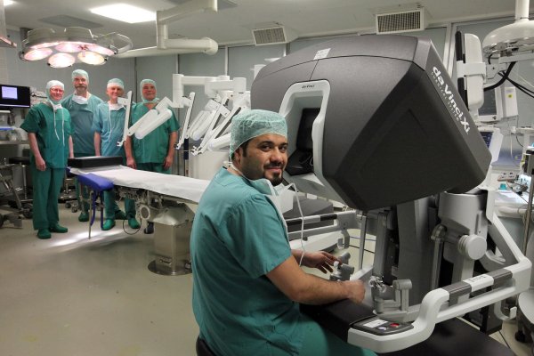 An der Konsole kann Dr. Ihab Abutabanjeh die vier Arme des Roboters „Da Vinci" steuern. Dahinter am Tisch stehen (von links) Prof. Dr. Wolfgang Hiller, Prof. Dr. Karl-Dietrich Sievert, Dr. Alfons Gunnemann und OP-Manager Karl-Heinz Nimczewski. - © Bernhard Preuss
