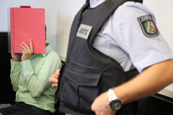 Die Angeklagte verdeckt beim Prozessauftakt ihr Gesicht mit einem roten Aktendeckel. - © Holger Kosbab