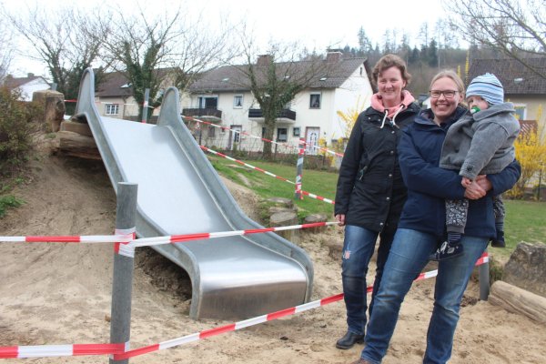 Kitaleiterin Stefanie Blome (links) und die Vorsitzende des Kita-Fördervereins Nicole Reker mit Sohn Mats (2) stehen vor der gesperrten Rutsche in der Kita "Pusteblume". Die Kinder haben die Rutsche in den vergangenen Jahren fast komplett unterhöhlt, sodass sie nun vom Bauhof gesperrt werden musste, da unter anderem der Fallschutz nicht mehr gegeben ist. Zudem hält ein Igel dort derzeit seinen Winterschlaf. - © Michaela Weiße