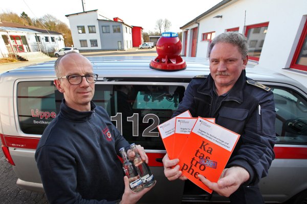 Vorsorge für den Notfall fängt mit ein paar Flaschen Wasser auf Vorrat an und das dürfen ruhig ein paar mehr sein, als Hans-Dieter Lödige hier in der Hand hält. Was genau, steht unter anderem in der Broschüre, die Kreisbrandmeister Wolfgang Kornegger zeigt. Für das Foto haben beide zudem eine mobile Sirene/Lautsperecheranlage aufs Autodach montiert. - © Bernhard Preuss
