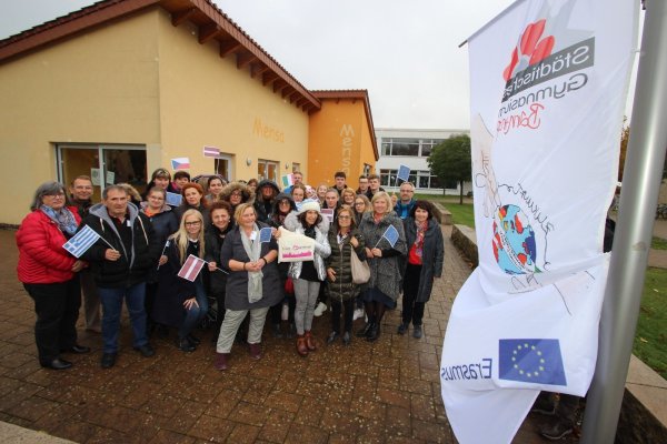 An der Erasmus-Flagge stehen Schulleiterin Gabriele Schmuck (links), Koordinatorin Anke Nagel (Mitte, mit Europa-Fähnchen), weitere Lehrer, Gastlehrer und Schüler. - © Jens Rademacher