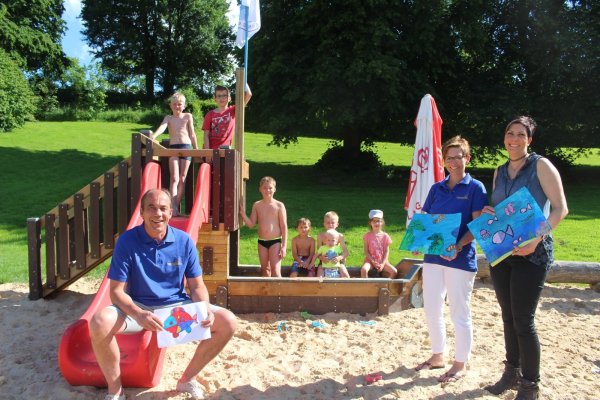 Piraten ahoi: (vorn, von links) Betreiber Rolf Stanislawski , Dagmar Schultz, Vorsitzende des Fördervereins, und die Künstlerin Marion Doxie Delaubell präsentieren die Fische, die die Schüler für die noch triste Mauer im Freibad gemalt haben. Die Kinder (hinten, von links) Jano (10), Leon (12), Lucas (10), Ruben (5), Jerome (9), Fynn (1) und Emilia (6) haben auf dem neuen Piratenschiff, das von der SPD gesponsert wurde, sehr viel Spaß. - © Michaela Weiße