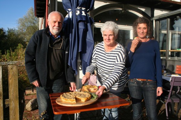 Mit alten Apfelsorten: Heike Bergmann (Mitte) schneidet den selbst gebackenen Apfelkuchen an. Willi Hennebrüder und Susanne Weege freuen sich, zu probieren. - © Kirsten Fuhrmann