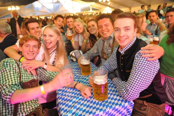 Zahlreiche Gäste erscheinen in traditionellen Dirndl und Krachledernen im Festzelt. Dazu fließt bayerisches Bier, und von der Bühne erklingt passende Musik. - © Nicole Ellerbrake