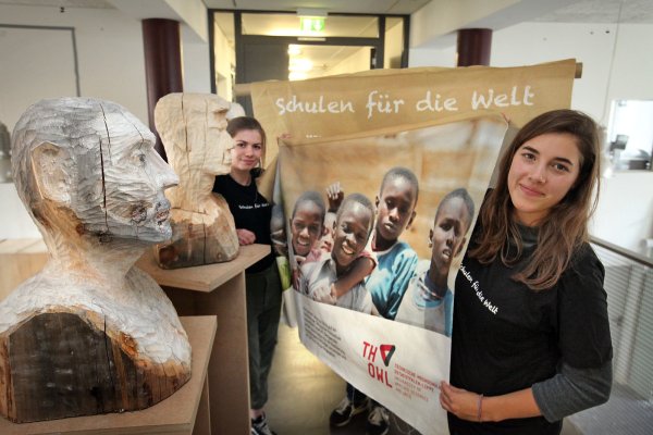 Lara Nellißen (rechts) und Tabea Pape halten das Banner. Die Holzköpfe und viele weitere Kunstwerke werden bei der Auktion versteigert. - © Bernhard Preuß