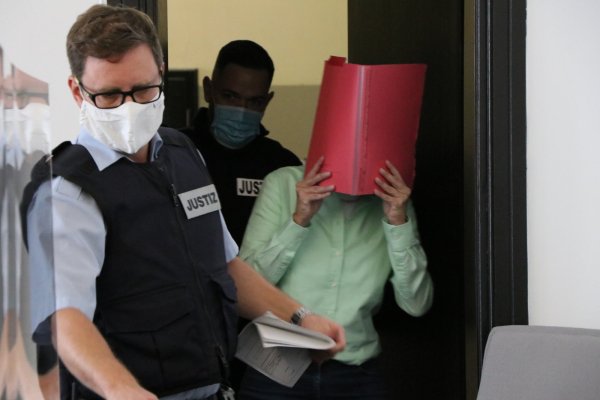 Die Angeklagte verdeckt ihr Gesicht mit einem roten Aktendeckel. - © Holger Kosbab