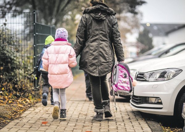 Überbehütend: Eine Mutter trägt ihrer Tochter den Schulranzen zum Unterricht. - © dpa