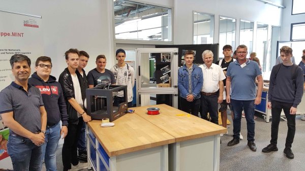 Technik, die begeistert: Die Schüler Fateh, Mike, Luca, Tim, Michael, Anthony, David und Jarno von der Heinrich-Drake-Realschule präsentieren stolz ihren Drucker und Transportwagen. Techniklehrer Morteza Atrsaie (links), Thomas Mahlmann vom zdi-Zentrum Lippe.MINT (Zweiter von rechts) und Günter Schröder von der Firma Weidmüller (Vierter von rechts) freuen sich. - © Kreis Lippe