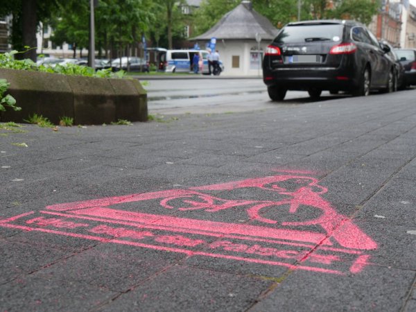 Das Geisterradler-Piktogramm verdeutlicht: Hier bist du falsch. Im Hintergrund sprechen die Polizisten Roger Berkel und Jörg Thelaner Radfahrer an, die an der Paulinenstraße auf dem Bürgersteig unterwegs sind. - © Jost Wolf