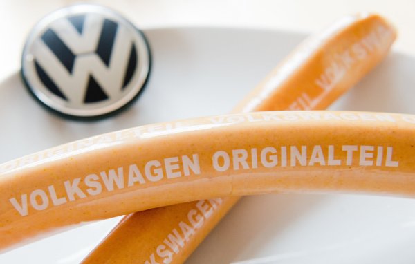 Zwei Currywürste mit der Aufschrift "Volkswagen Originalteil" liegen auf einem Teller mit VW-Logo. Die Streichung in einer Kantine ruft auch die heimischen Landwirte auf den Plan. - © Julian Stratenschulte
