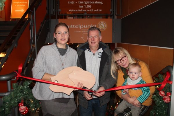 Jochen Dubbert duchschneidet das rote Band, während Rabea Kruel (links) das „Spendenschwein-Brettchen" und Claudia Beckmeier den kleinen Josse hält. - © Judith Stracke