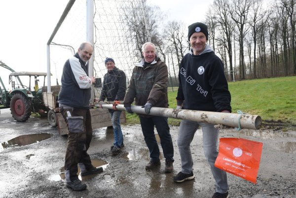 Pressesprecher Frank Bracht (von links) packt mit den Helfern Friedhelm Ernst, Johannes Lange und Stefan Mildenberge beim Auszug mit an. Das Tor findet sein neues Zuhause auf einer Wiese an der Mehrzweckhalle. Dort soll weiter gebolzt werden. - © Nicole Ellerbrake