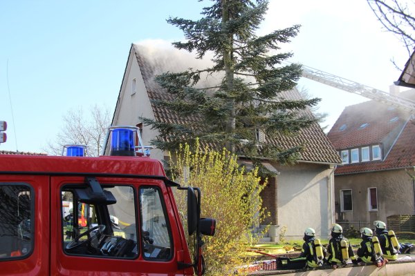 Das Dachgeschoss brennt: Feuerwehrleute versuchen, das Einfamilienhaus in der Goekenbrede in Pottenhausen zu retten. - © Wolfgang Becker