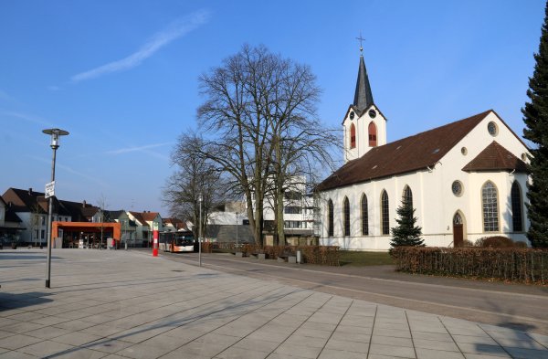 Die Haltestelle Leopoldshöhe Markt liegt am neu gestalteten Marktplatz. Weil Busse – anders als ursprünglich geplant – die Haltestelle von der Herforder Straße (hinten) anfahren, dafür am Café Orange eine scharfe Rechtskurve nehmen müssen und dabei über Ausweichflächen fahren, sind dort bereits Schäden entstanden. - © Martin Düsterberg