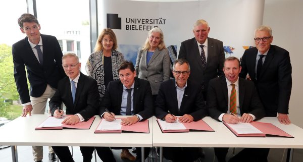 Wichtige Unterschrift: Rainer Norden (Aufsichtsratsvorsitzender des evangelischen Klinikums Bethel, vorne v. l.), Michael Ackermann (Geschäftsführer Klinikum Bielefeld), Gerhard Sagerer (Rektor der Universität Bielefeld) und Johannes Hütte (Geschäftsführer Klinikum Lippe) unterzeichnen die Kooperationsvereinbarung für das Universitätsklinikum OWL. Frank Lohkamp (Geschäftsführer der medizinischen Fakultät, hinten v. l.), Claudia Hornberg (Gründungsdekanin), Isabel Pfeiffer-Poensgen (NRW-Wissenschaftsministerin), Karl-Josef Laumann (NRW-Gesundheitsminister) und Stephan Becker (Kanzler der Universität Bielefeld) schauen ihnen dabei zu. - © Wolfgang Rudolf