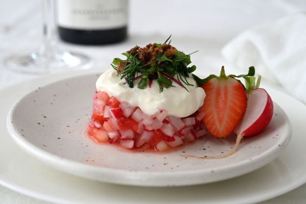 Der Erdbeer-Radieschen-Salat wird mit einem Servierring in Form gebracht. Darauf gibt es als Topping Ziegen-Feta-Creme, Kräutersalat und geröstete Krümel vom Schwarzbrot. Serviert wird er mit einem alkoholfreien Rosé. - © Julia Uehren/Deutsches Wein-Institut/dpa-tmn