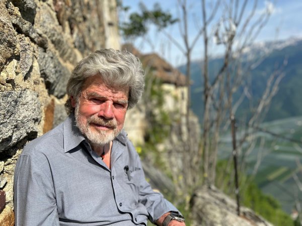 Der Bergsteiger Reinhold Messner sitzt an seinem Schloss Juval auf einer Bank. - © Christoph Sator/dpa