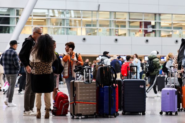 Am Flughafen in Düsseldorf stehen Reisende am Samstagmorgen mit ihren Koffern im Abflug-Terminal. - © Christoph Reichwein/dpa