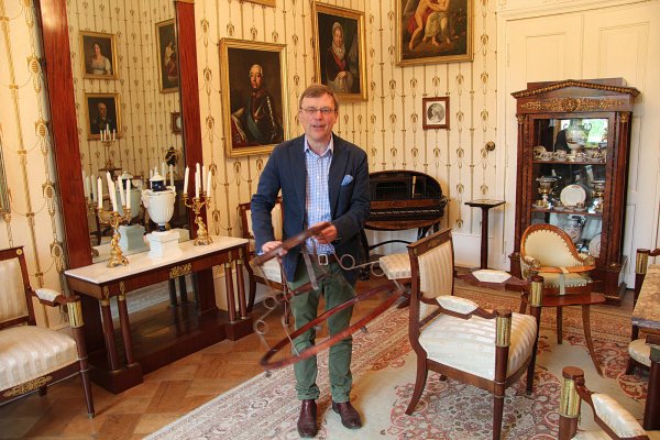 Der fliegende Holländer: So heißt das Laufstühlchen, das Stephan Prinz zur Lippe hier zeigt. Mit ihm sind früher die Prinzen übers fürstliche Parkett getobt. Rechts der Empire-Kinderstuhl, in dem auch die jüngste Generation der Familie gesessen hat. - © Thorsten Engelhardt