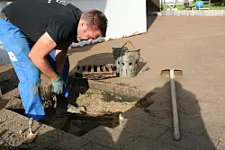 Aufr&auml;umarbeiten: Mark J&auml;ger gr&auml;bt einen Kanal frei, der durch den Matsch verstopft ist. Sein ganzer Hof, der an Werkstatt und Tankstelle an der Extertalstra&szlig;e grenzt, war vollgelaufen. - &copy; Kirsten Fuhrmann