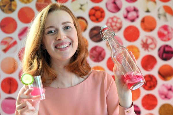 Model Christin hält auf der Internationalen Süßwarenmesse ein Glas Wodka in der Hand, das mit Sweet Shots-Bonbonmasse versetzt wurde. - © Federico Gambarini/dpa